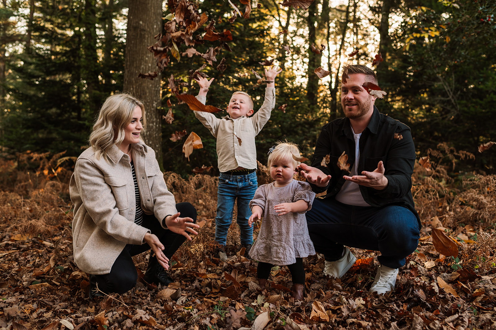 Family throwing autumn leaves in photoshoot